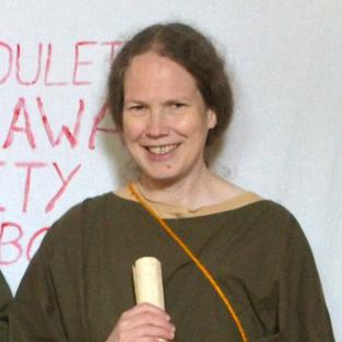 A photograph of the author, Eleanor Dickey, in Roman costume, holding a scroll.