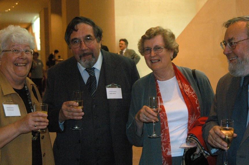 2 women and 2 men - Jill, Robin, Pat and Roger - standing in a row holding champagne glasses. They are standing in a large hall and behind them are other attendees at the event.