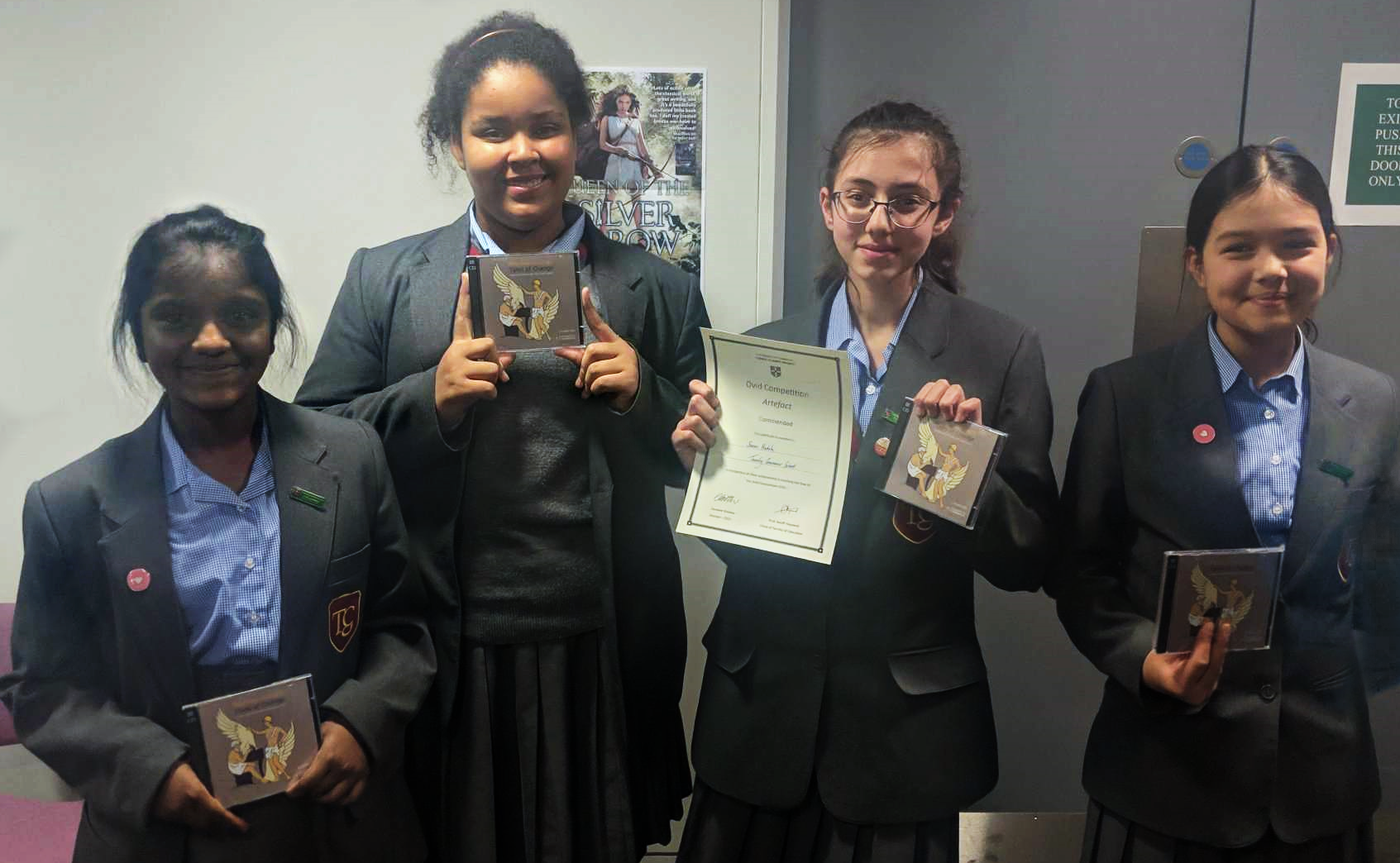 Four students holding certificates and prizes