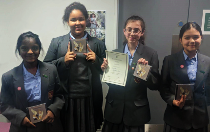 Four students holding certificates and prizes